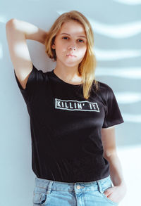 Portrait of serious beautiful woman leaning on wall