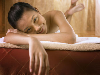 Close-up portrait of young woman lying on bed