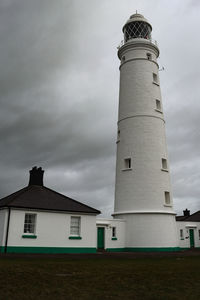 Lighthouse by sea against sky