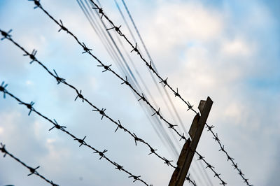 Low angle view of barbed wire against sky