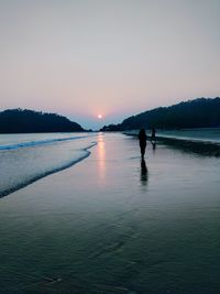 Silhouette man on beach against sky during sunset