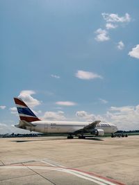 Airplane on airport runway against sky