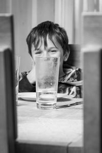 Portrait of boy drinking glass on table