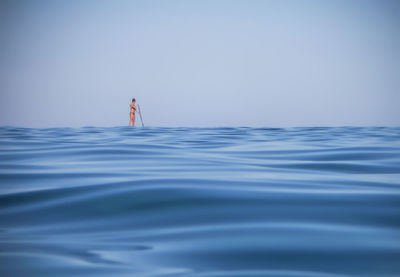 Woman paddleboarding in sea against sky