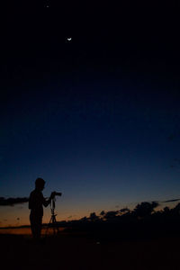 Silhouette man photographing against sky during sunset