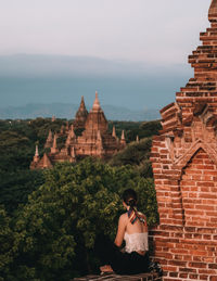 Rear view of woman standing outside temple against building