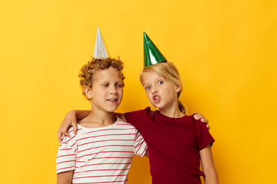 Portrait of sibling against yellow background