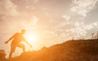 Man on rock against sky during sunset