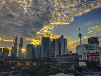 Buildings in city against cloudy sky during sunset