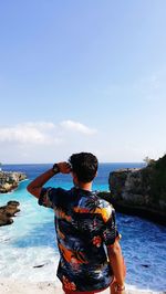 Rear view of man looking at sea against sky