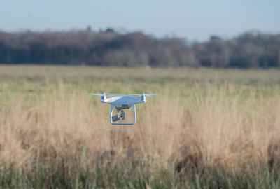 Helicopter flying over field against sky