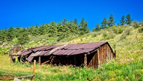 Abandoned house on field against clear blue sky