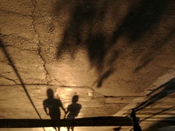 Shadow of people on street against wall