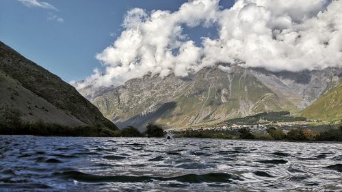 Scenic view of sea by mountains against sky