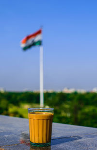 Tea in glass on retaining wall against indian flag
