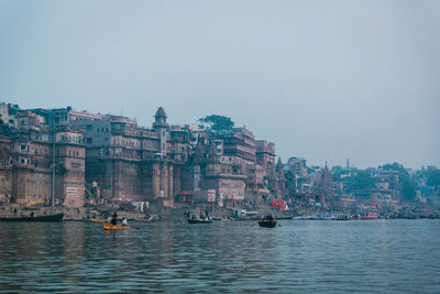 Buildings by sea against clear sky