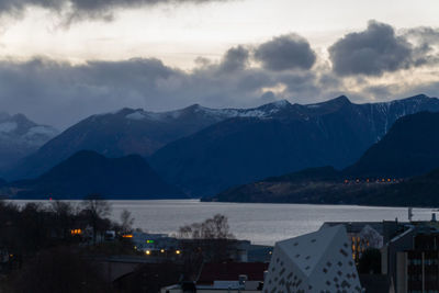 Scenic view of townscape by mountains against sky at dusk