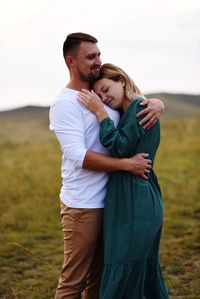 Young couple sitting on land against sky