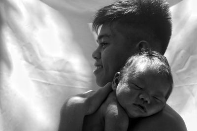 Smiling father holding cute baby son against curtain