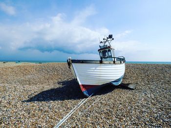 Ship moored on beach against sky