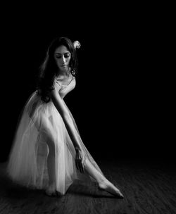 Young woman dancing against black background