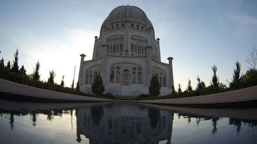 Reflection of historic building in pool against sky