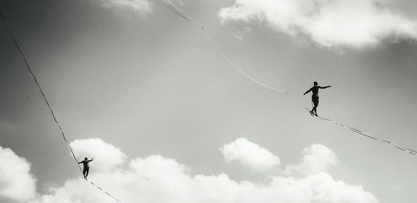 Low angle view of silhouette man paragliding against sky