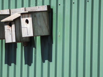 Wooden birdhouses on green corrugated iron wall