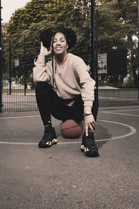 Portrait of young woman sitting on footpath