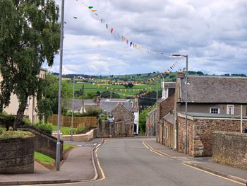 Road by buildings in city against sky