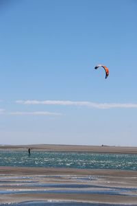 Man paragliding on sea against sky