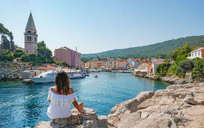 Woman from behind, looking towards a picturesque old seaside town.