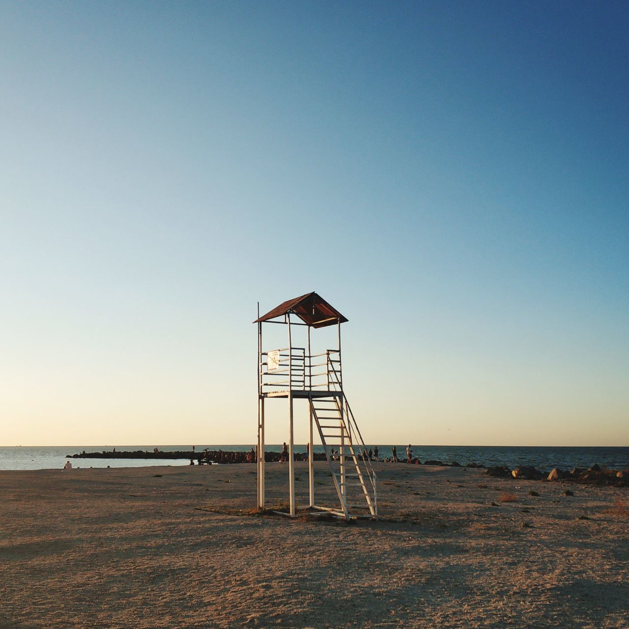 sky, lifeguard hut, sea, beach, water, lifeguard, land, horizon, hut, man made structure, horizon over water, nature, ocean, sand, tower, coast, clear sky, architecture, built structure, lookout tower, security, scenics - nature, protection, tranquility, shore, observation point, copy space, tranquil scene, beauty in nature, no people, body of water, blue, day, outdoors, sunset, travel destinations, sunny, building exterior