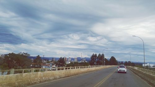 Cars on road in city against sky