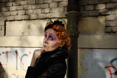 Portrait of young woman looking away against wall