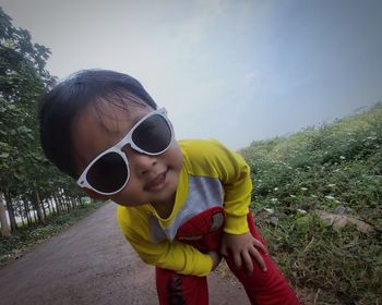 Boy wearing sunglasses standing on land against sky