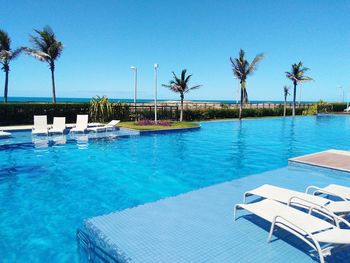 Swimming pool by sea against clear blue sky