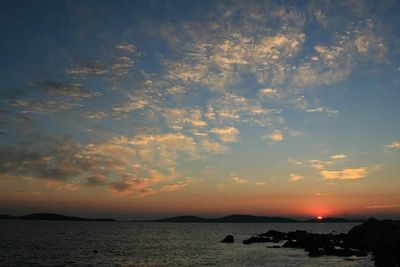 Scenic view of sea and silhouette mountains against sky during sunset