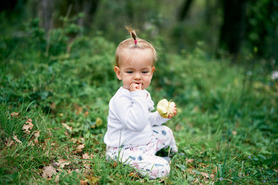 Cute girl eating apple sitting on grass