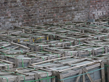 Collection of woorden crates filled with gray bricks against a red brick wall