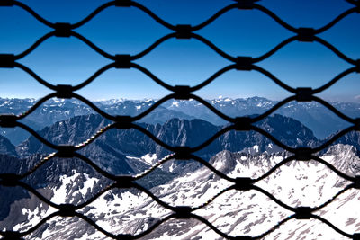 Close-up of chainlink fence against sky during winter