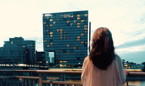 Rear view of woman standing against buildings in city