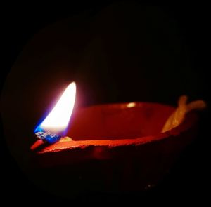 Close-up of lit candle against black background