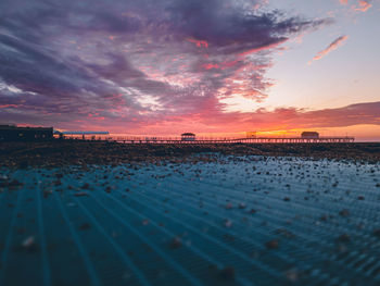 Surface level of beach against sky during sunset