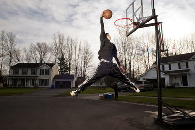 Man playing with basketball hoop against sky