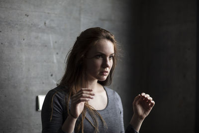 Portrait of young woman looking away against wall