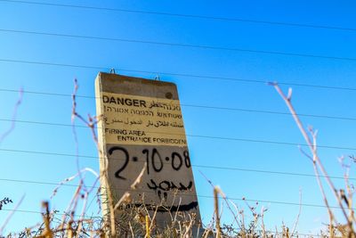 Low angle view of information sign against blue sky