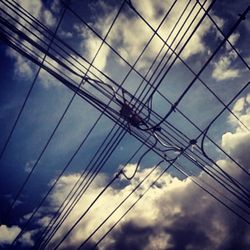 Low angle view of electricity pylon against cloudy sky