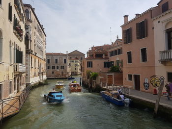 Canal amidst buildings in city against sky