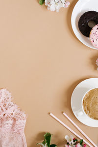 Stylish pale pink women's accessories, a cup of coffee and flowers on a beige background.